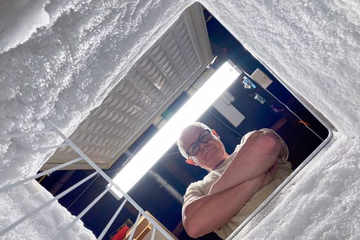 freezer con ghiaccio e uomo che lo osserva