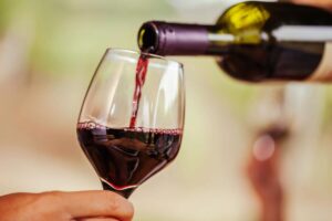 Versare vino rosso dalla bottiglia nel calice