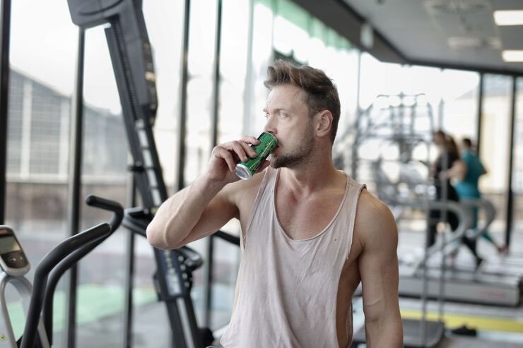 Ragazzo in palestra beve da lattina verde