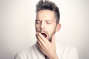 uomo che sbadiglia con la mano davanti alla bocca